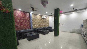 A spacious lobby with a patterned wall, a black leather sofa, and a green pillar. - HOTEL VCR INN (New Delhi)
