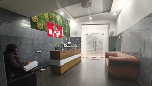 A reception area with a reception desk, a seating area, and a green wall with plants. - HOTEL VCR INN (New Delhi)