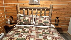 A bed with a quilt featuring animal prints, wooden headboard, and two bedside tables with lamps.