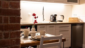 A kitchen with white cabinets, a coffee maker, and a dishwasher. - Arcano | Studio dla Dwojga | Przytulne wnętrze (Bydgoszcz)