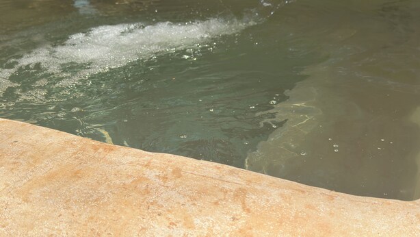 Una piscina con agua salpicando, rodeada por un borde de piedra.