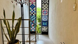 Un pasillo con una escalera que lleva a una puerta decorada con patrones geométricos coloridos.