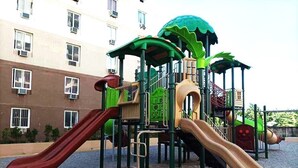 Un terrain de jeux doté de plusieurs toboggans et d’aires d’escalade, entouré d’un bâtiment avec de nombreuses fenêtres.
