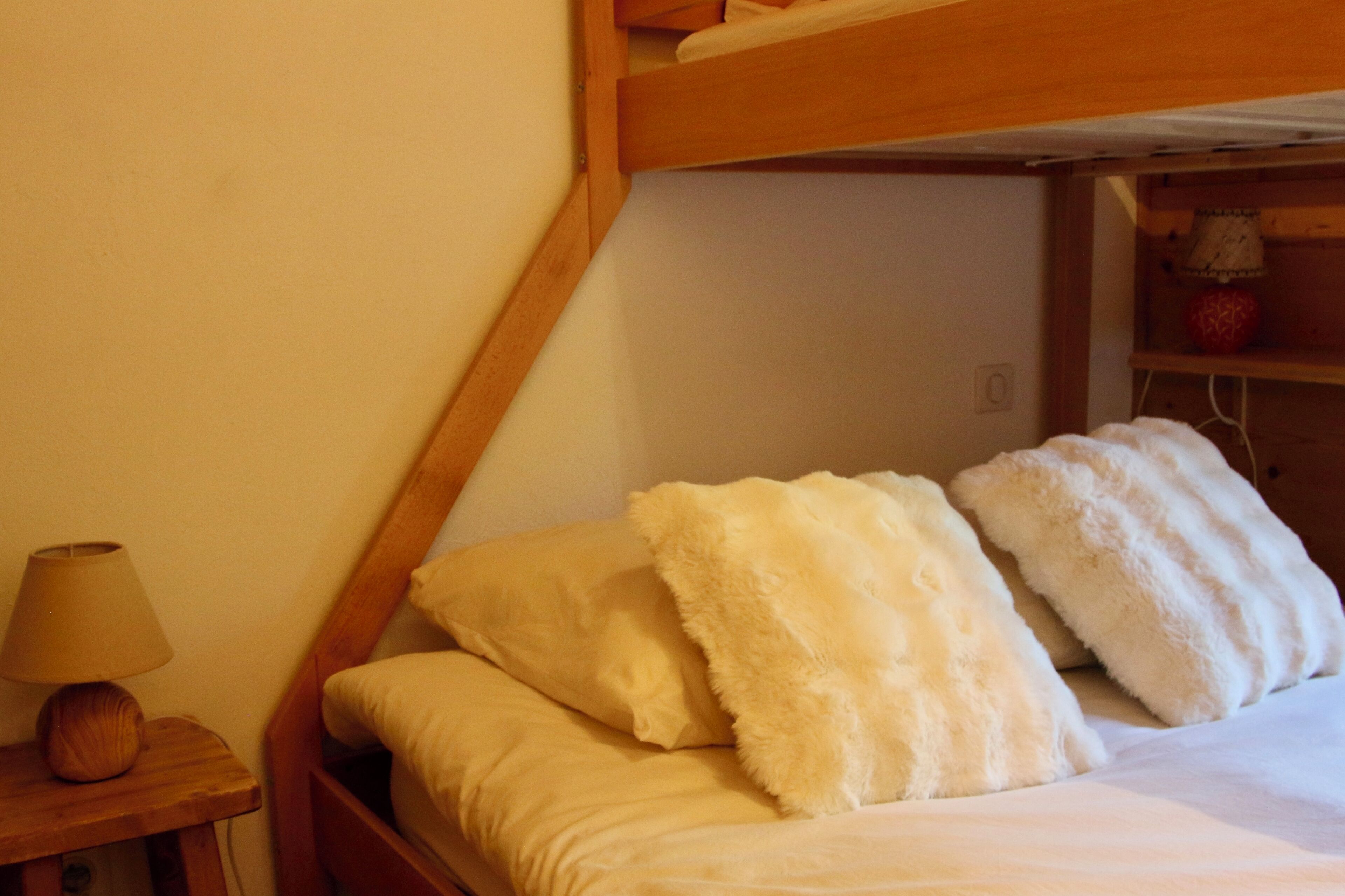 Ein Etagenbett mit weißer Bettwäsche und einem Holzkopfende.