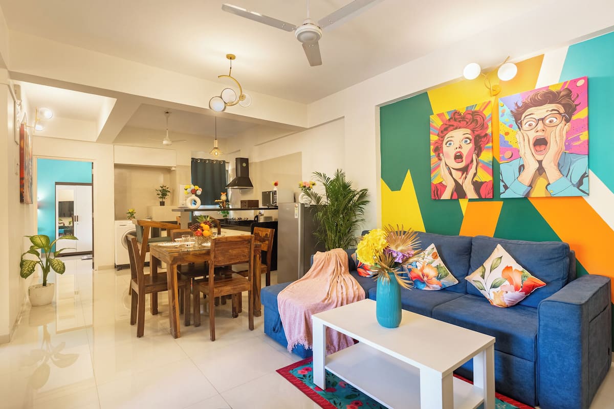 Una sala de estar moderna con un sofá, una mesa de comedor y una cocina al fondo.