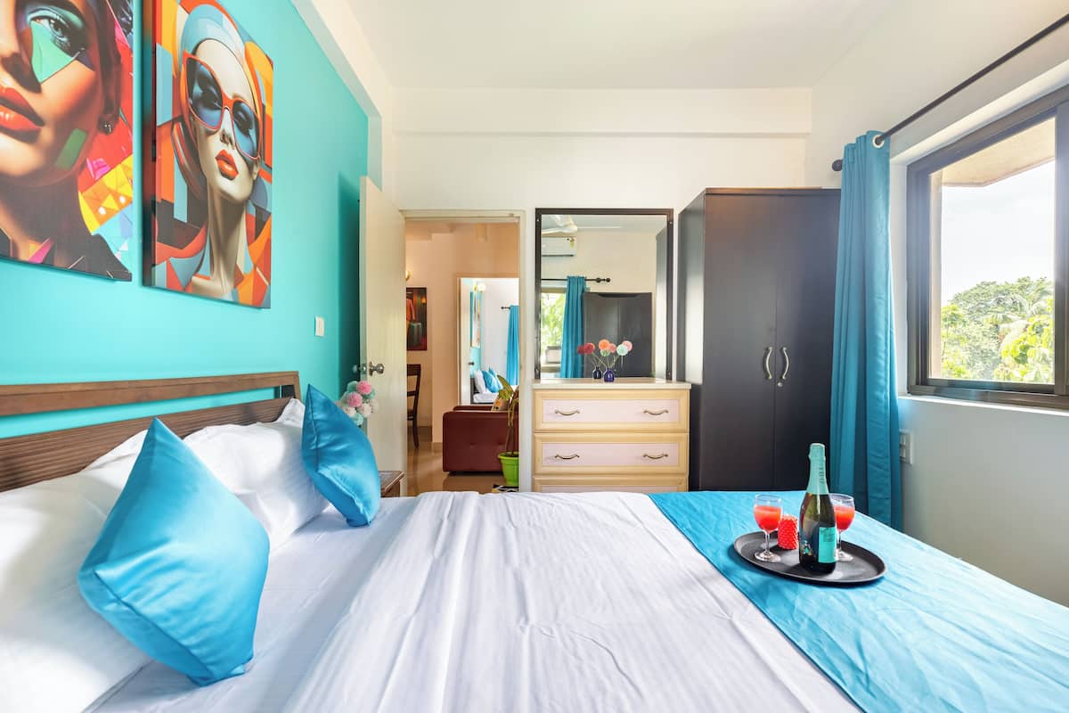 Una habitación de hotel con cama, cómoda, espejo y ventana con cortinas.