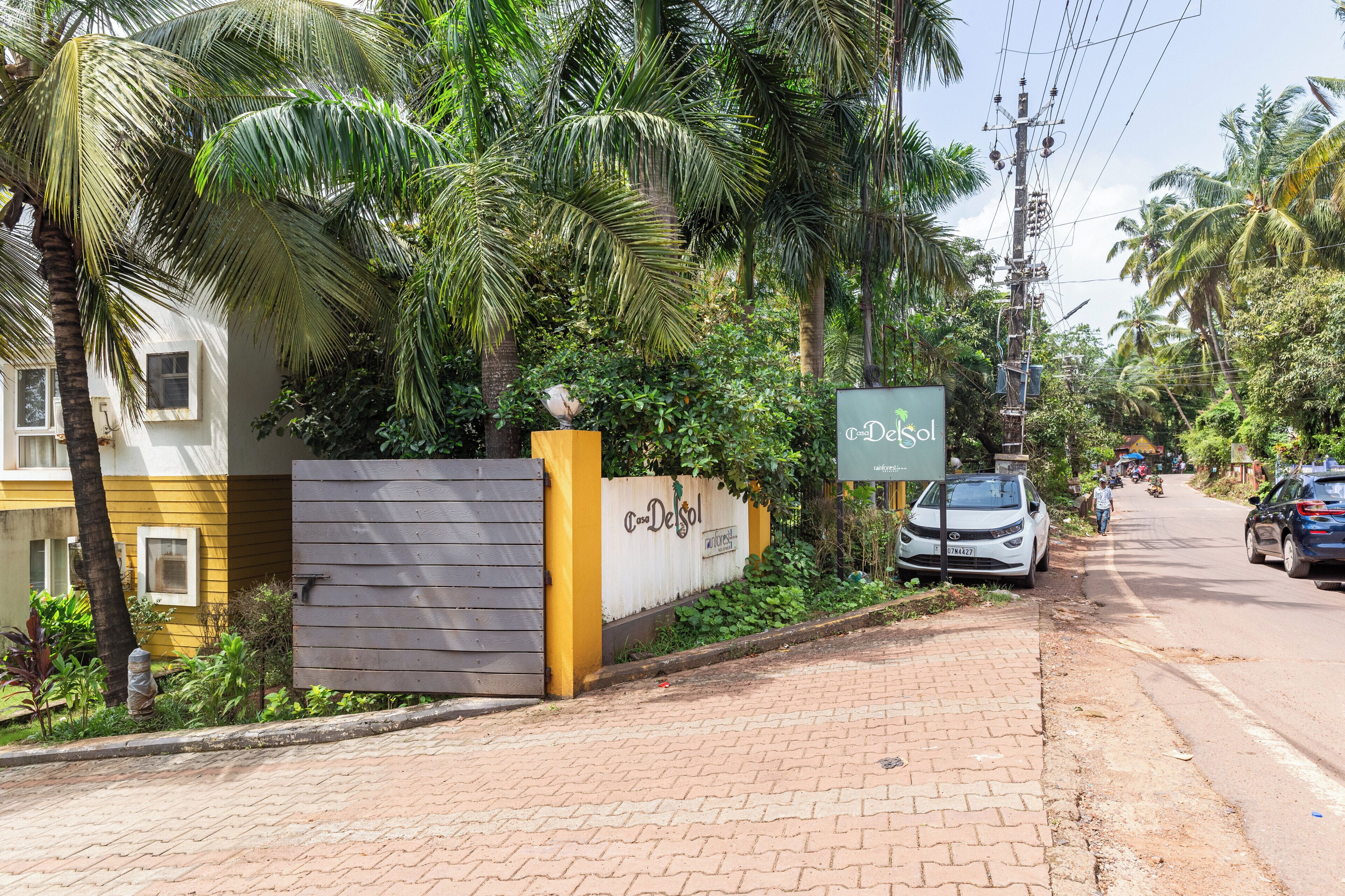 A gated entrance with a sign for 'DeSol' hotel, a paved sidewalk, and a road with cars.