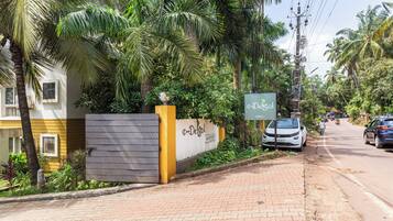 A gated entrance with a sign for 'DeSol' hotel, a paved sidewalk, and a road with cars.