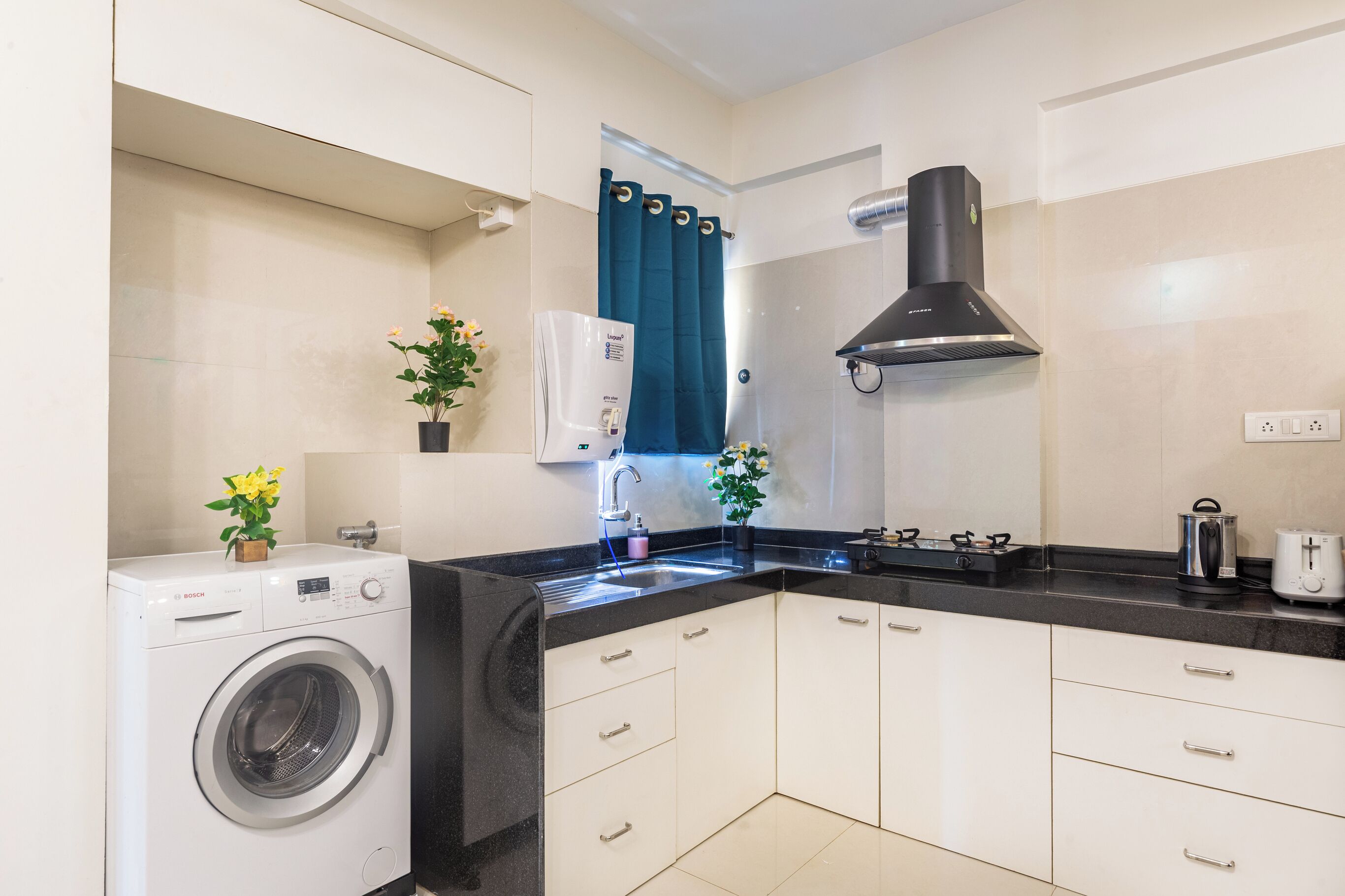 A compact kitchen with a washing machine, a stove, and a sink.