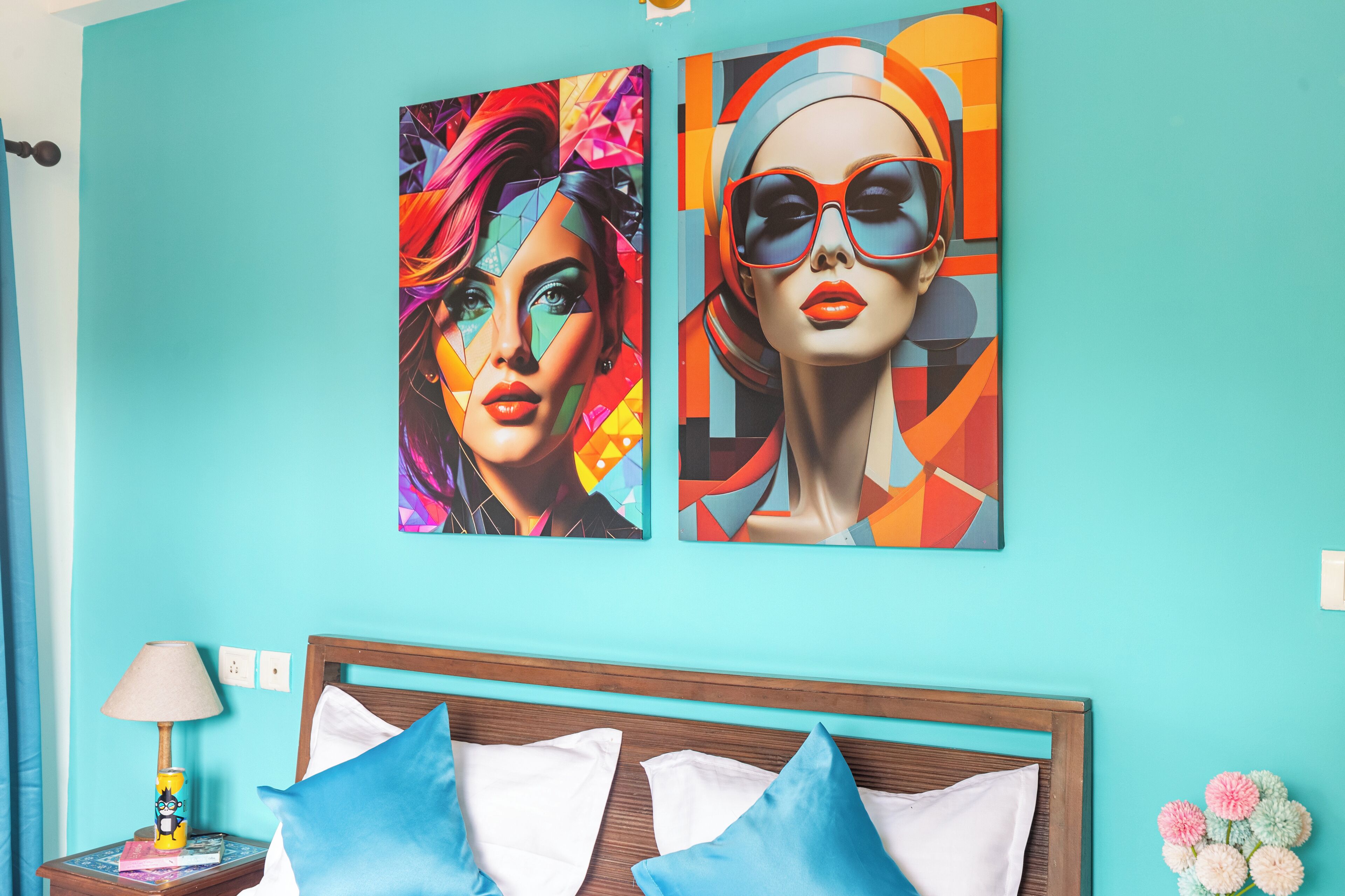 A bedroom with a teal wall, a wooden headboard, and two paintings.
