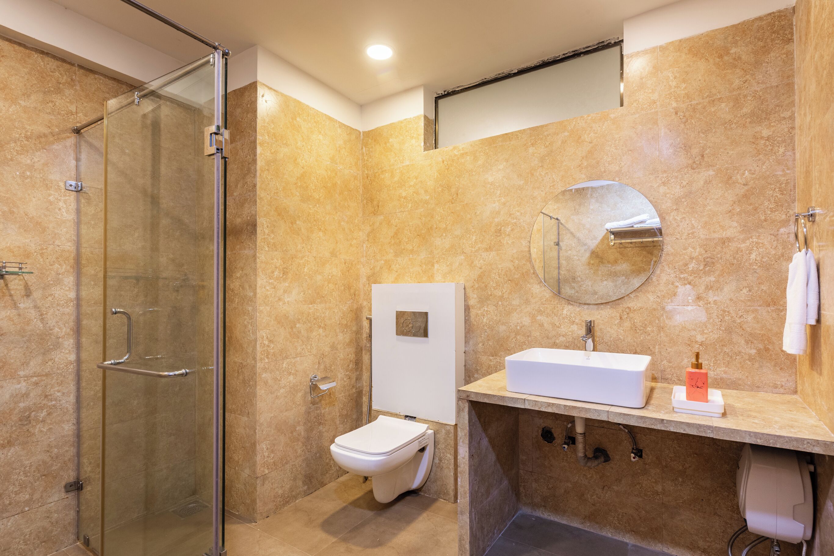 A modern bathroom with a glass-enclosed shower, a white toilet, and a sink with a mirror above.