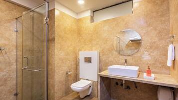 A modern bathroom with a glass-enclosed shower, a white toilet, and a sink with a mirror above.