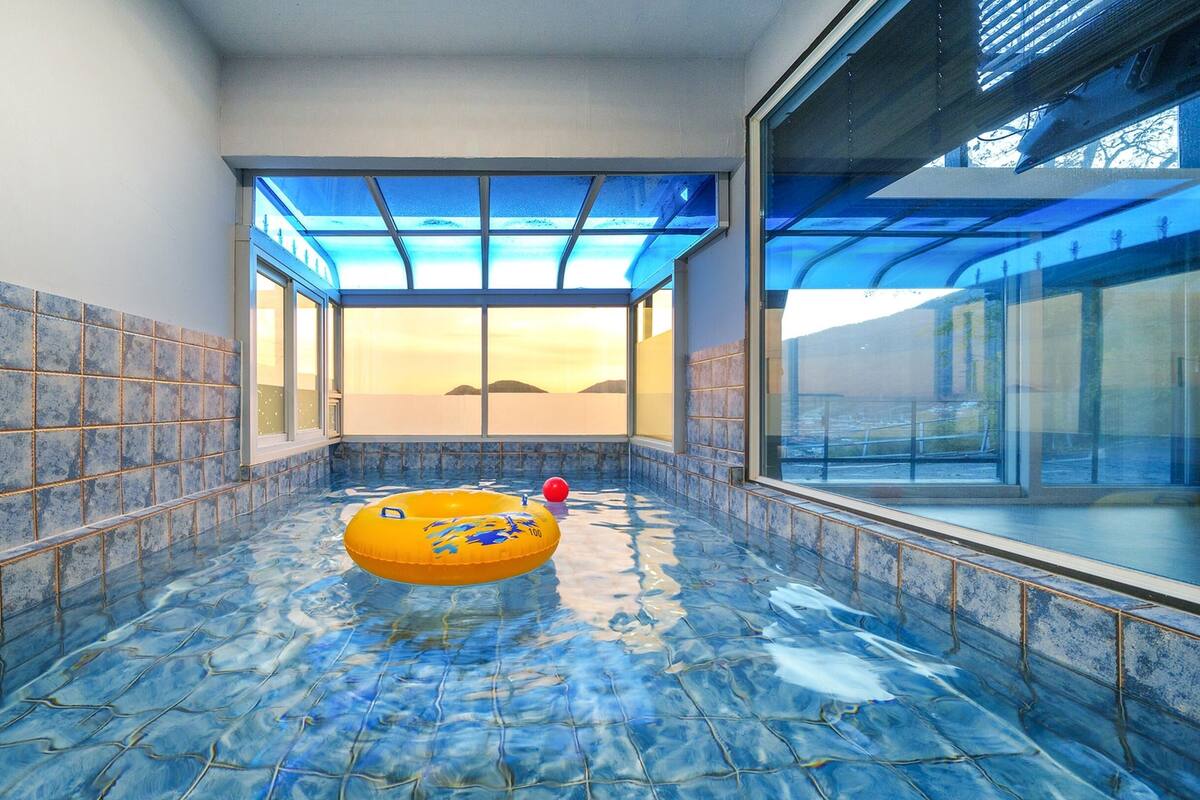 A modern indoor pool with a clear view of the sunset through large windows.