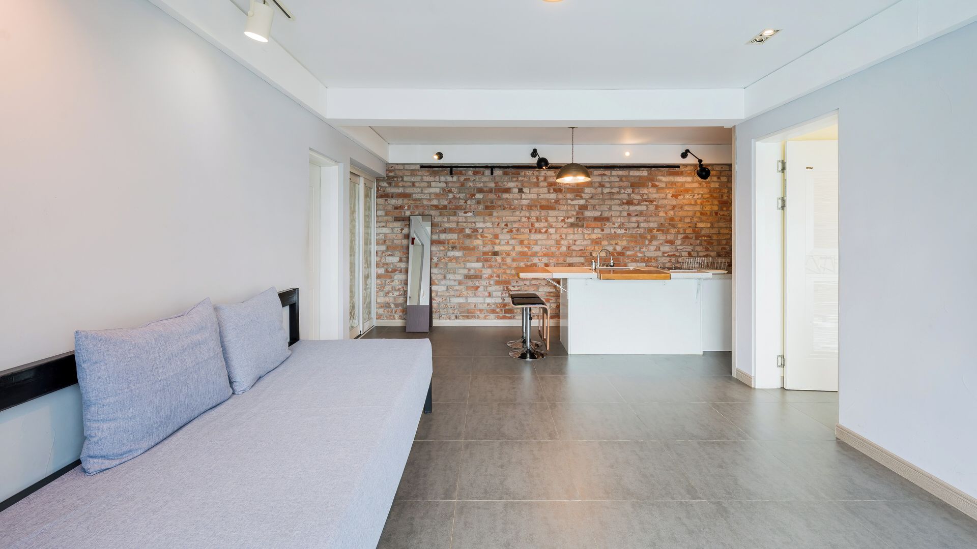 Un intérieur moderne comprenant un lit, un coin cuisine et un mur en briques.