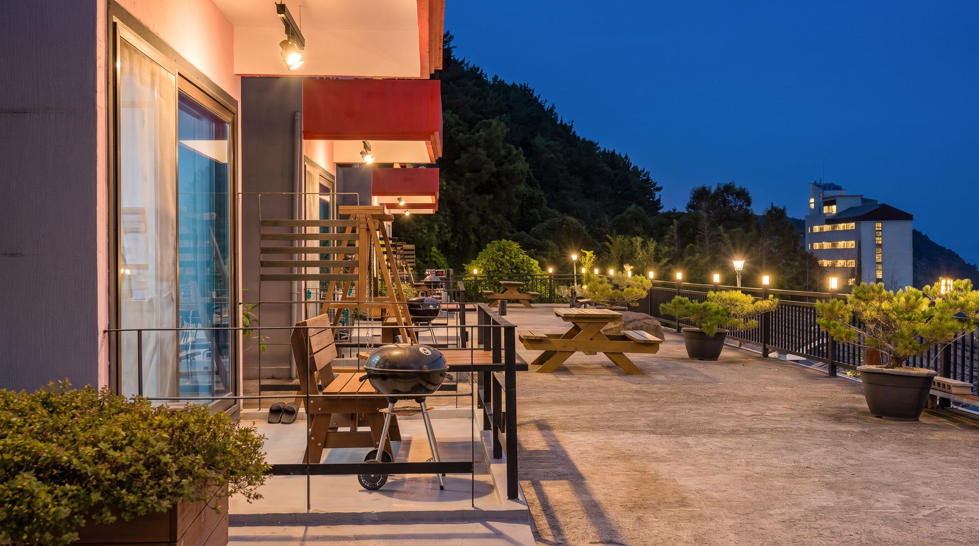 An outdoor patio area with a barbecue grill, seating, and potted plants.