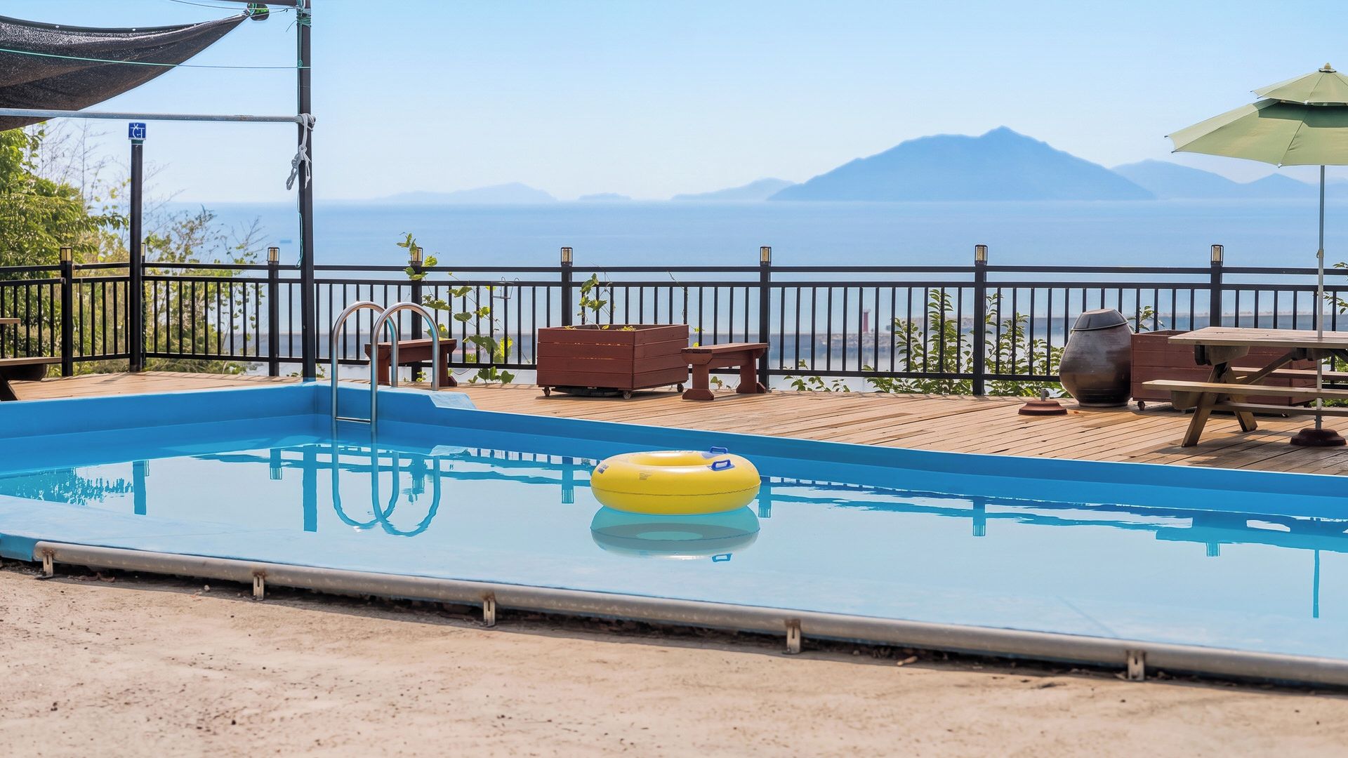 A swimming pool with a view of mountains, a deck with seating, and a patio area.