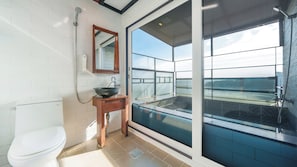 Un baño moderno con inodoro, lavamanos y un gran ventanal de vidrio que da a un balcón.