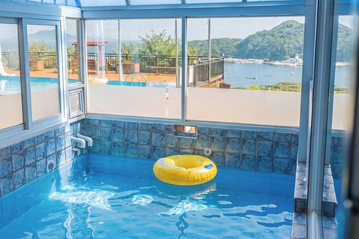 Una piscina interior con vista a un cuerpo de agua y colinas.