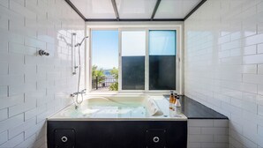 Un baño moderno con bañera, ducha y ventana con vistas.