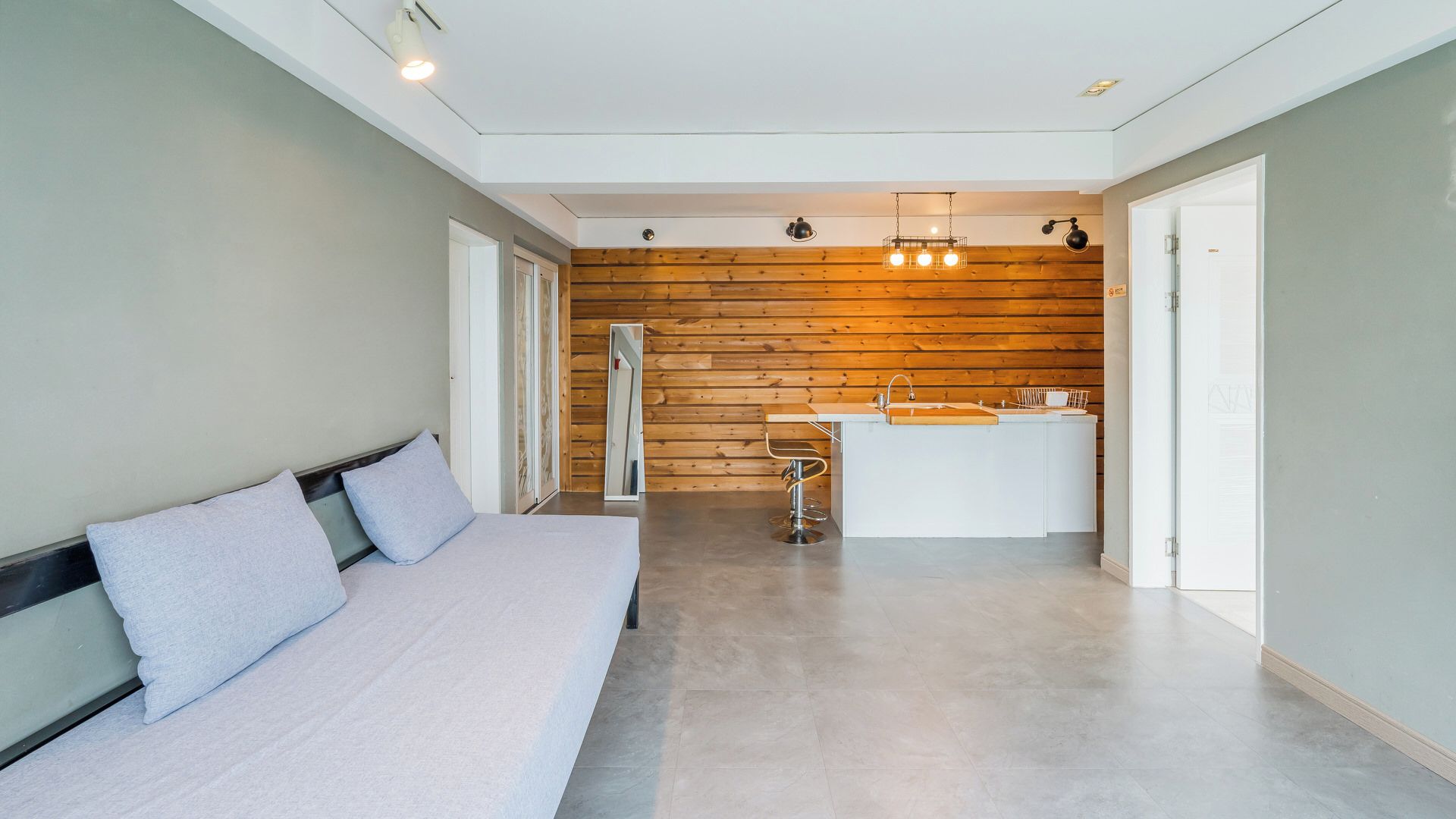 Un dormitorio moderno con una cama grande, una pared de madera y una pequeña kitchenette.