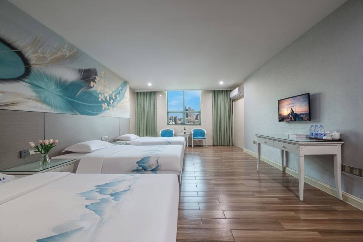 Une chambre d’hôtel avec deux lits, un bureau, une chaise, une télévision et une vue sur la ville par la fenêtre.