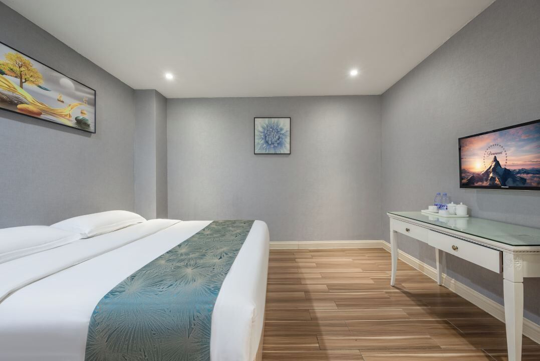 Een moderne slaapkamer met een bed, een glazen bureau en kunstwerken aan de wanden.
