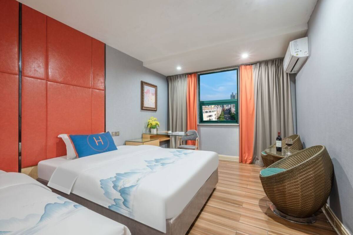 Une chambre d’hôtel  équipée d’un lit, d’un bureau, d’une chaise et d’une fenêtre donnant sur la ville.
