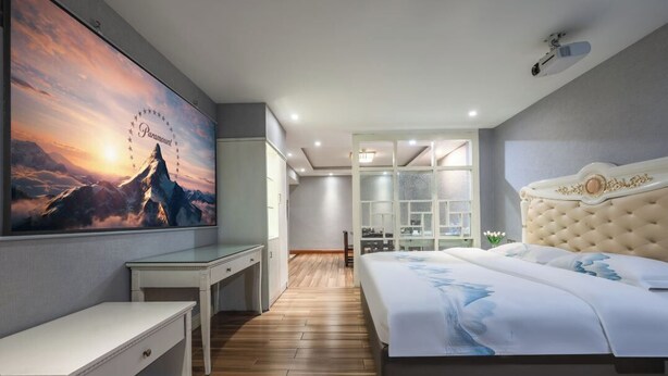 A modern bedroom with a large bed, a desk, and a view of the mountains. - xingduhuadujiudian (Quanzhou)