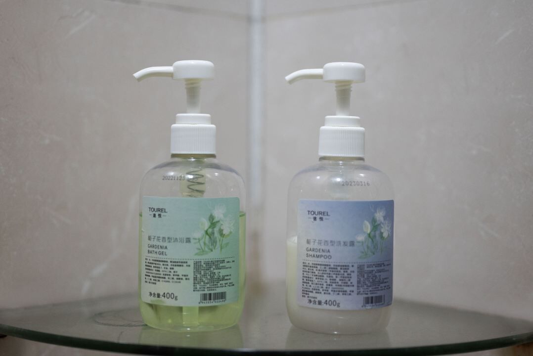Two bottles of toiletries on a glass shelf.