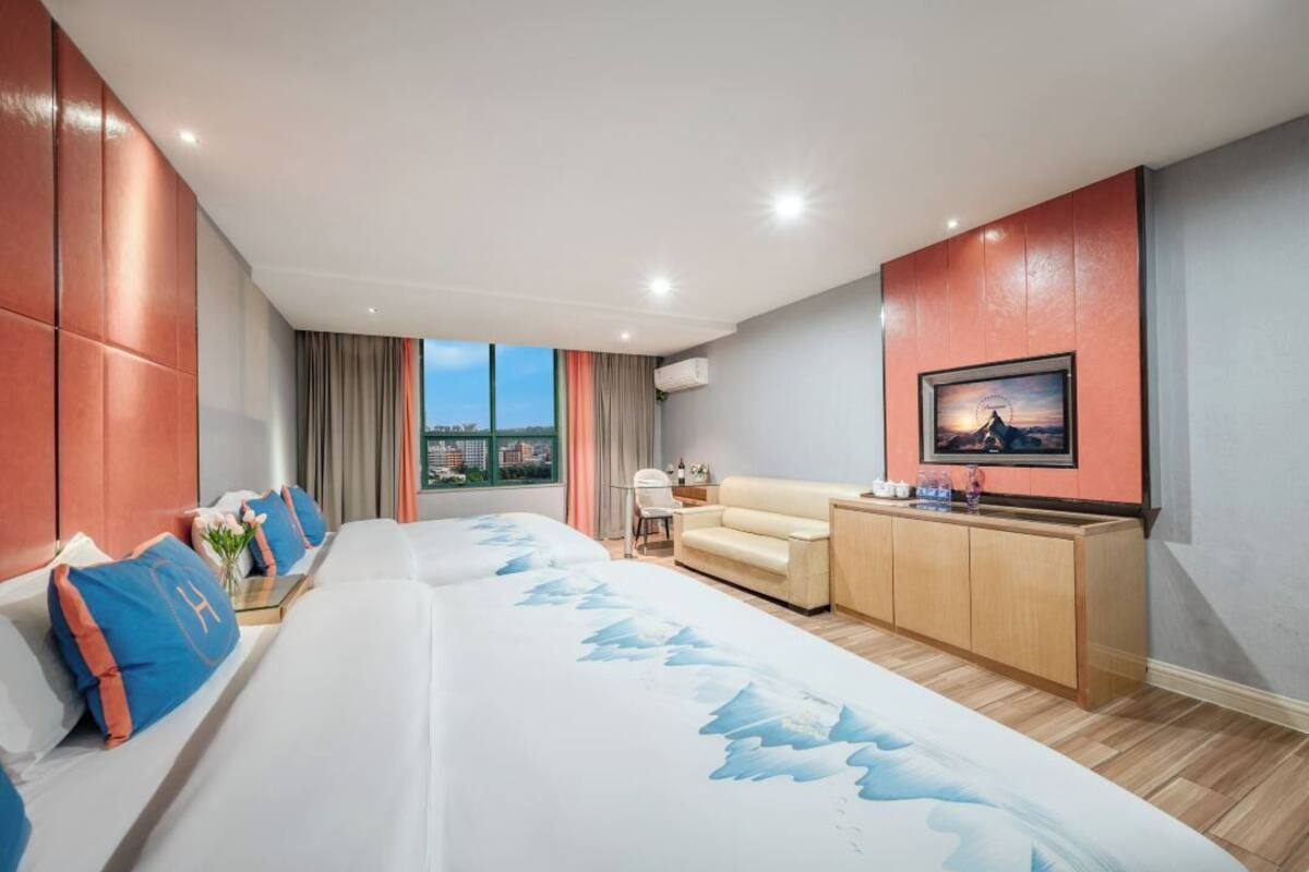 Une chambre d’hôtel moderne dotée d’un grand lit, d’un canapé, d’une télévision et offrant une vue sur la ville.