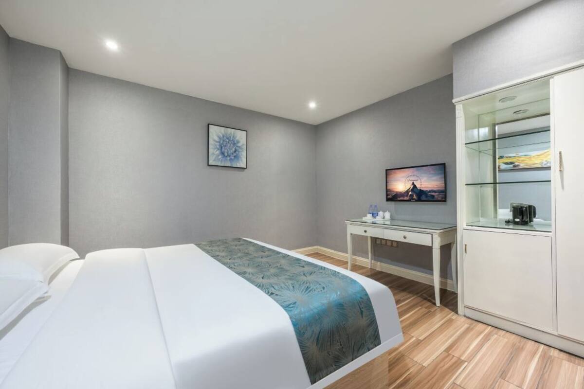Une chambre d’hôtel équipée d’un lit, d’un bureau, d’une télévision et d’une armoire.