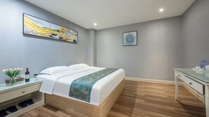 A modern bedroom with a bed, a nightstand, a desk, and artwork on the walls. - xingduhuadujiudian (Quanzhou)