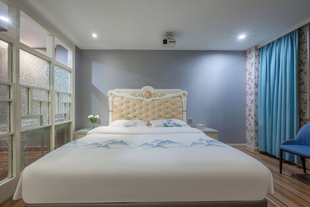 Un dormitorio con una cama grande, una mesita de noche, una silla y una ventana con vidrio esmerilado.