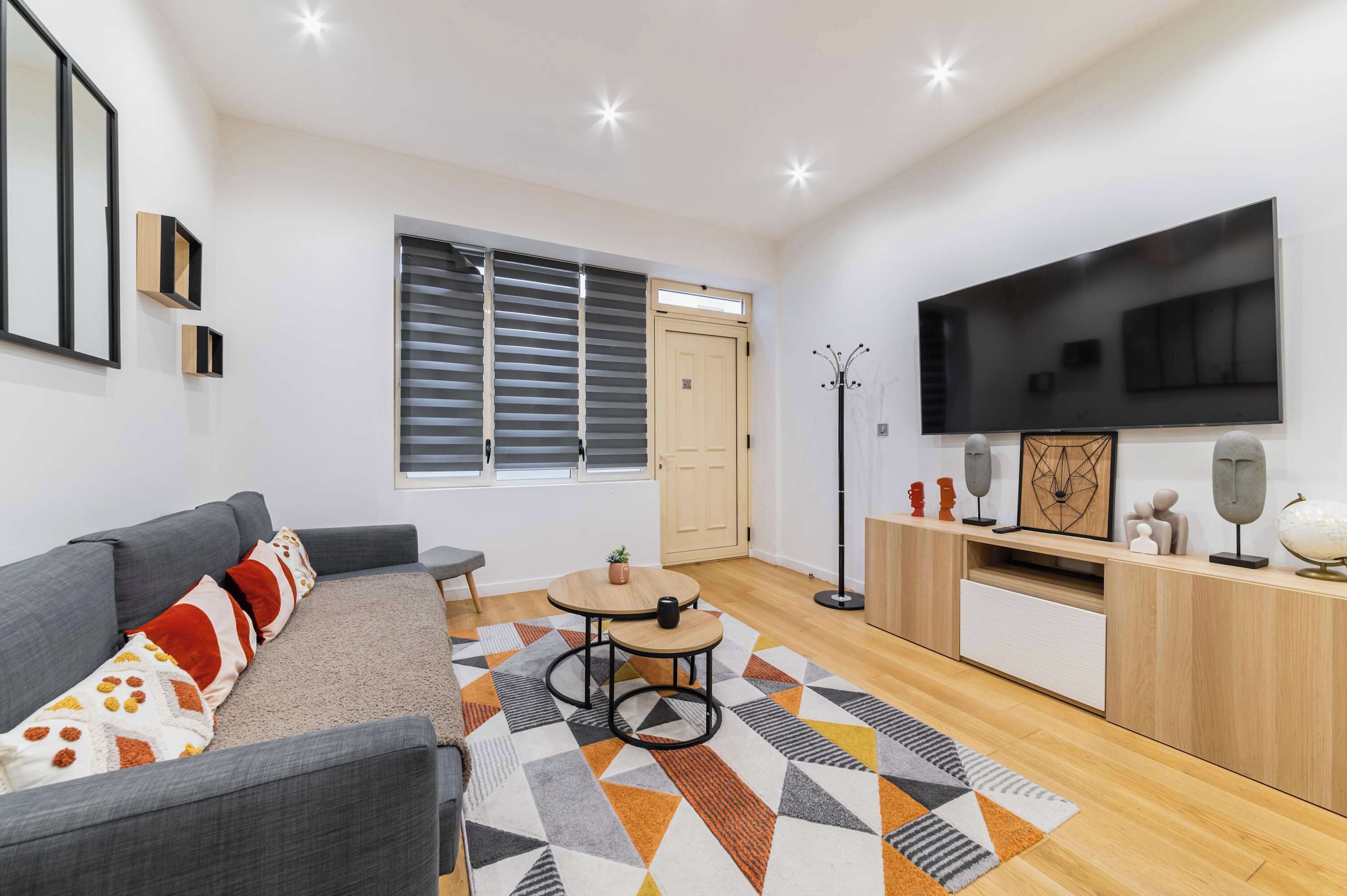 A modern living room with a sofa, a coffee table, a TV, and a patterned rug.
