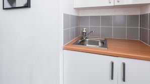 A modern kitchen with white cabinets, a stainless steel sink, and a tiled backsplash. - Jardin des Plantes View Studio w/ High-Speed WiFi (Paris)