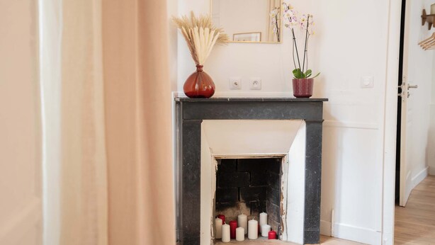 A room with a fireplace, a mirror, and a door. - Logement cosy metro Pierre Lachaise - 3P (Paris)