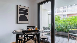 Ein Essbereich mit Tisch, Stühlen und Blick auf einen Balkon mit Grünpflanzen.