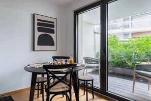 Ein Essbereich mit Tisch, Stühlen und Blick auf einen Balkon mit Grünpflanzen.
