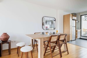 Un comedor con una mesa de madera, cuatro sillas, un jarrón y un espejo en la pared.