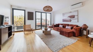 Una sala de estar moderna con un sofá, una mesa de centro y un ventanal grande.