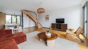 Una sala de estar moderna con un sofá, una mesa de centro, un televisor y una escalera.