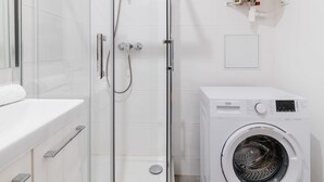 A modern bathroom with a glass-enclosed shower, a white washing machine, and a toilet. - Studio agreable et bien placee - Paris 18 - 2P (Paris)
