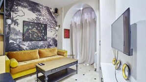 A living room with a sofa, a coffee table, a TV, and a mural on the wall.