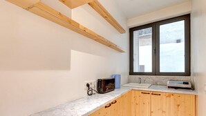 Eine Küche mit Holzausstattung, einer Marmorarbeitsplatte, einem Fenster und einer eingebauten Mikrowelle.