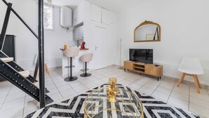 Ein modernes Wohnzimmer mit Treppe, Fernseher, Spiegel und Essbereich.