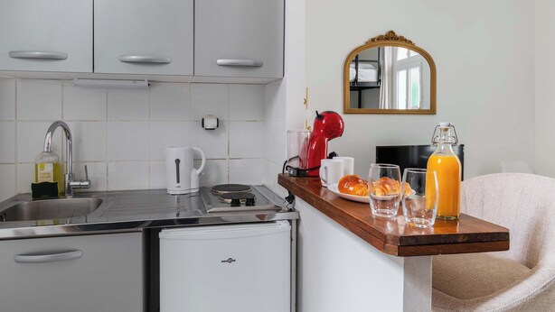 Eine kompakte Küchenzeile mit Spüle, kleinem Kühlschrank, Wasserkocher, Toaster und Kaffeemaschine.