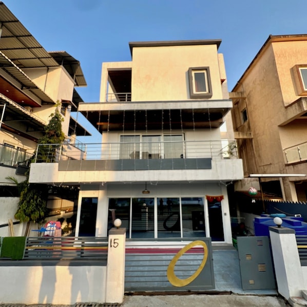 Un edificio moderno de dos pisos con techo plano, ventanas amplias y un balcón.