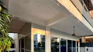 A modern building with large glass windows, a red carpet, and a metal railing. - Greystone 4BHK Pvt Pool by Stellar Stays (Mawal)