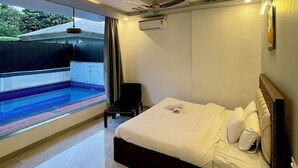 A modern hotel room with a large bed, a small bedside table, and a view of a swimming pool. - Greystone 4BHK Pvt Pool by Stellar Stays (Mawal)