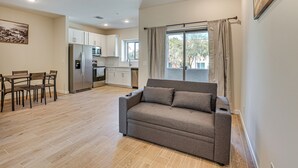A modern kitchen with white cabinets, a built-in refrigerator, and a dining area with a wooden table and chairs.